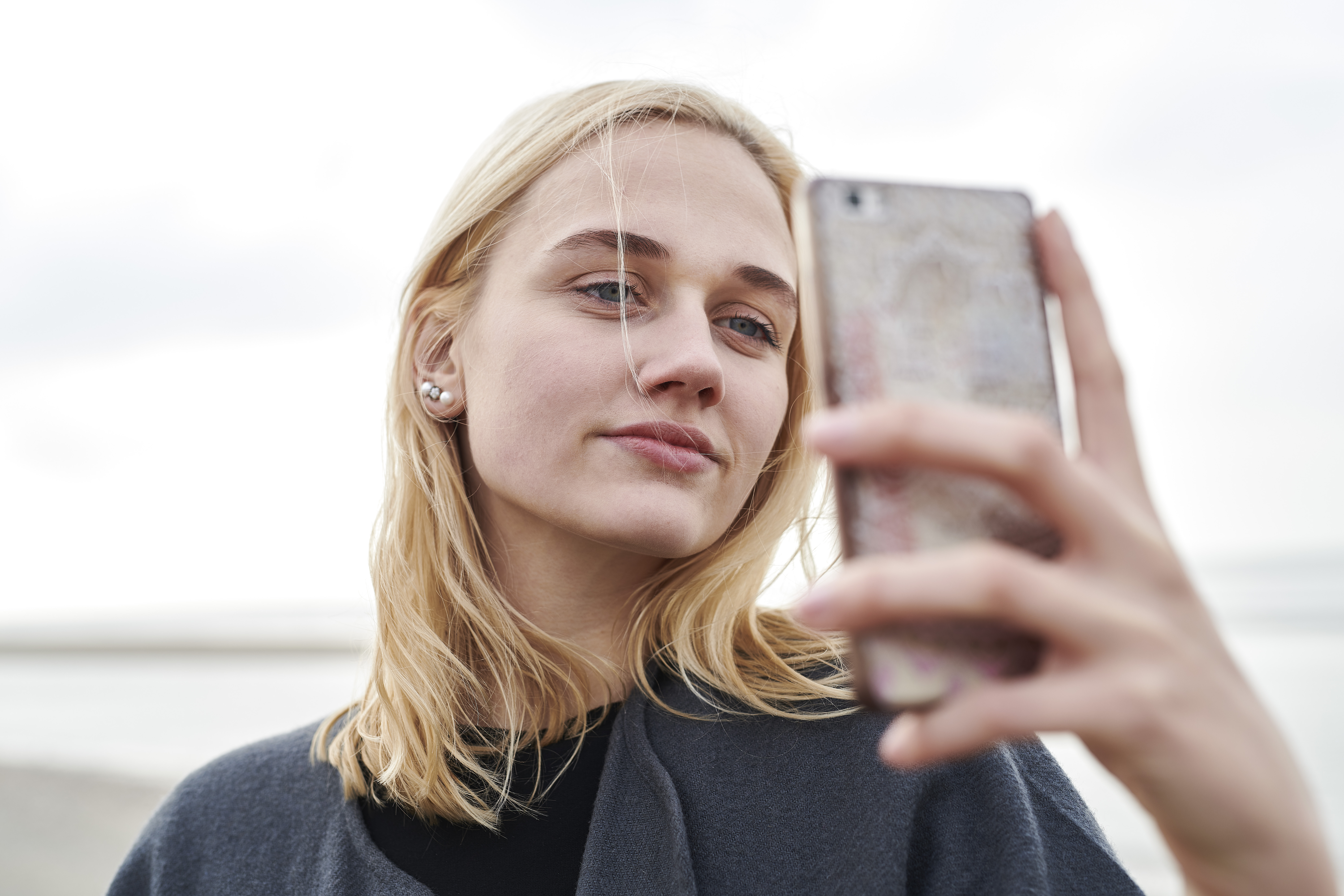 Portrait of blond young woman taking selfie with smartphone on the beach